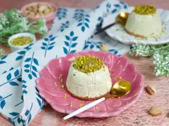 Delizioso semifreddo al pistacchio, guarnito con crema e granella di pistacchi, servito su un piatto rosa.