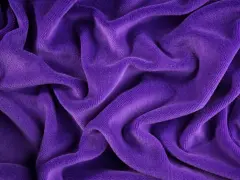 Ondeggiante velour tessuto viola, morbido e invitante, con pieghe profonde che creano un gioco di luci e ombre.