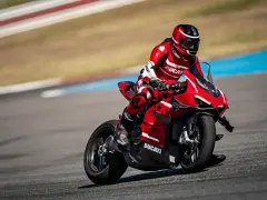 Motocyklista w czerwonym kombinezonie śmiga na torze wyścigowym na swoim czerwonym Ducati Panigale V4.