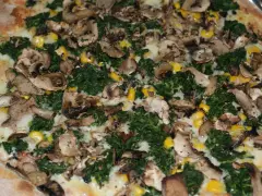 Pyszna pizza ze szpinakiem, grzybami i kukurydzą, obficie posypana serem.