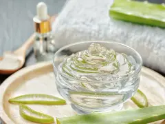 Un bol de gel aloe vera, des tranches d'aloe vera et une cuillère en bois. Découvrez les bienfaits du gel aloe vera pour votre peau.