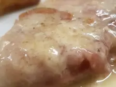 Cotoletta alla bolognese succulenta, con prosciutto e formaggio fuso, un classico della cucina emiliana.