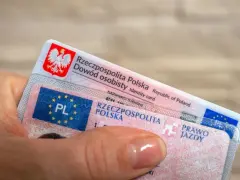 Dłoń trzyma polski dowód osobisty i prawo jazdy. To dokumenty, które pozwalają na swobodne podróżowanie, a prawo jazdy bezterminowe daje spokój na lata.
