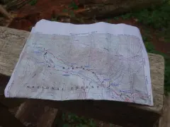Mapa szlaku grzbietu pacyficznego z zaznaczonymi punktami i rzekami, leżąca na drewnianej ławce.
