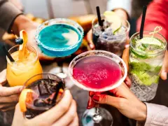 Kolorowe, popularne drinki w rękach przyjaciół. Różowe, niebieskie, pomarańczowe i zielone koktajle z owocami i lodem.