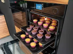 Ciasto z mikrofalówki kontra ciasto z piekarnika: na trzech poziomach piekarnika pieką się babeczki w kolorowych papilotkach.