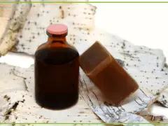 Brązowa buteleczka z płynem i kostka mydła na tle kory brzozowej. To naturalne produkty, a dziegieć co to? To właśnie taki ciemny, aromatyczny produkt.