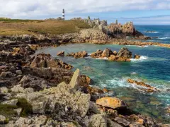 Phare noir et blanc sur une côte rocheuse et sauvage d'Ouessant. Combien de temps pour visiter Ouessant ? Une journée suffit pour admirer ce paysage.
