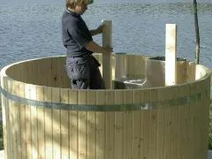 Man bygga badtunna vid sjön. Träet är nytt och redo för montering.