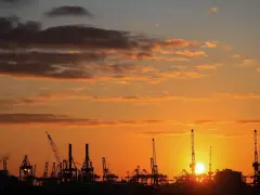 Silhouetten von Kränen im Hamburger Hafen bei Sonnenuntergang. Perfekt für die Pfingstferien in Hamburg.