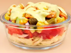 Sałatka gyros w szklanej misce z kurczakiem, kukurydzą, ogórkiem i sosem.