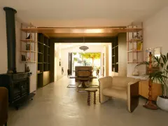 Aménagement maison en longueur : salon avec poêle, étagères et vue sur salle à manger et jardin.