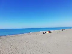 Słoneczny dzień na plaży w Marina di Bibbona. Ludzie odpoczywają na piasku, a morze lśni w słońcu.