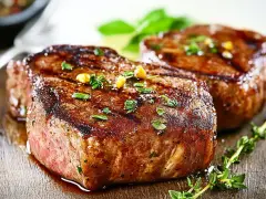 Due succulenti filetti di manzo grigliati, guarniti con erbe aromatiche e chicchi di pepe, pronti per essere gustati.