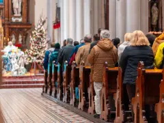 Ludzie siedzą w kościele przy choince. Czy w drugi dzień świąt trzeba iść do kościoła?