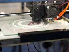 Głowica drukarki 3D tworzy biały okrąg na szklanej platformie. To część projektu drukarki 3d.