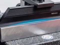 Precyzyjne pomiary 3D z użyciem wzorców Mitutoyo. Błękitne światło uwydatnia idealnie płaskie powierzchnie.