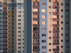 Widok na fasadę wielopiętrowych bloków mieszkalnych z balkonami i oknami.