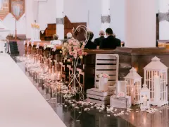 Romantyczna dekoracja kościoła na ślub samemu: płatki róż, świece, latarenki i kwiaty tworzą magiczną atmosferę.