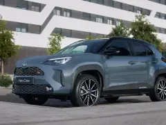 Szary Toyota Yaris Cross hybryda stoi na tle nowoczesnego budynku.