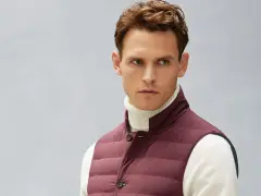 Uomo con gilet imbottito bordeaux sopra dolcevita bianco. Il gilet, un capo versatile, aggiunge stile e calore.