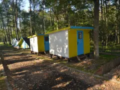 Kolorowe domki kempingowe w lesie, jak małe perły Krutyni, czekają na gości.