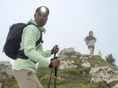 Randonneur ajustant son réglage bâton de marche, prêt à affronter la brume avec sa lampe frontale.