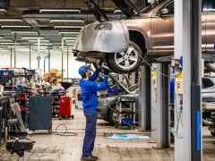 Mekaniker arbetar med en bil på en verkstad. Detta visar vad som ingår i bilservice, med verktyg och utrustning synliga.