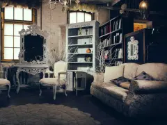Salotto con divano, poltrone, specchio barocco e librerie. Un esempio di arredamento massimalista che unisce elementi classici e decorazioni elaborate.