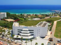 Widok z lotu ptaka na hotel Margadina Lounge Hotel z basenem i palmami, w tle błękitne morze i plaża.