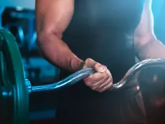 Muskulös arm som greppar skivstång i ett superset gym.