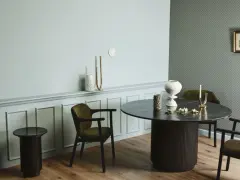 Ett runt matbord med mörka stolar skapar en inbjudande atmosfär. Utrymme runt matbordet ger plats för samtal och gemenskap.