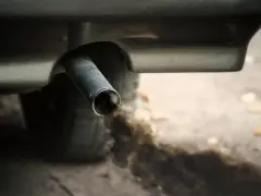 Z rury wydechowej wydobywa się gęsty, czarny dym, zanieczyszczając powietrze.