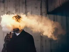 Hombre exhala una gran nube de vapor de su vaper. Se puede rellenar un vaper con agua para crear este efecto.