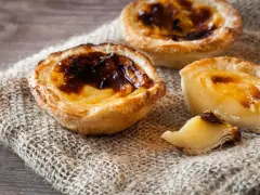 Tre krämiga portugisiska bakelser med karamelliserad yta, en klassiker inom portugisisk mat.