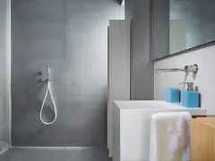 Bagno moderno con rivestimento doccia senza piastrelle effetto resina, lavabo bianco e accessori azzurri.