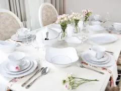 Eleganckie pomysły dekoracja stołu komunijnego: biała zastawa, bukieciki róż, świece i złote zdobienia.