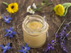 Vasetto di pappa reale, circondato da fiori blu e gialli. Chissà dopo quanto fa effetto questo prezioso nettare.