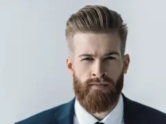 Mężczyzna z gęstą, rudą brodą, prezentujący jeden z popularnych rodzajów brody. Elegancki styl i zadbanie.