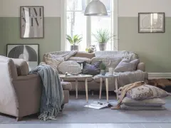 Vardagsrum i svensk stil med bekväm soffa, fåtölj och en sovande hund. Vårljus strömmar in genom fönstret och skapar en mysig atmosfär.