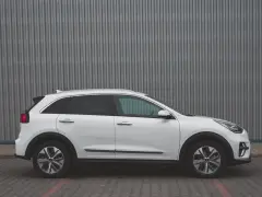 Biały Kia Niro EV widziany z boku na tle szarej, falistej ściany.