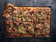 Pyszna pizza domowa przepis na blachę z szynką, pieczarkami i oliwkami. Idealna na rodzinne spotkanie.