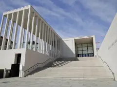 Moderne berlin architektur: James-Simon-Galerie mit langer Treppe und Säulengang vor blauem Himmel.