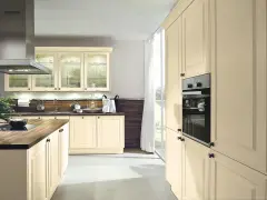 Jasna, biała kuchnia z drewnianym blatem i jasnoszarą podłogą. Wbudowany piekarnik i przeszklone szafki dodają elegancji.