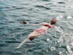 Une femme flotte paisiblement sur l'eau, profitant des ampoules eau de mer bienfaits pour la relaxation et le bien-être.