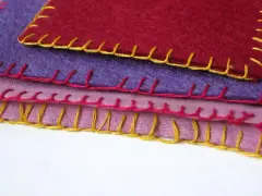 Tessuti colorati sovrapposti, rifiniti con un punto coperta giallo, rosa e rosso.
