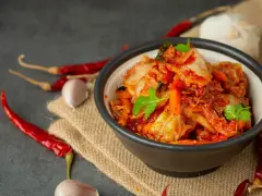 Miseczka z kimchi, obok suszone papryczki chili i czosnek.