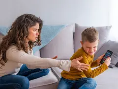Genervte Mutter streitet mit Sohn, der sein Handy nicht abgeben will. Mögliche ADHS-Erziehungsfehler im Fokus.