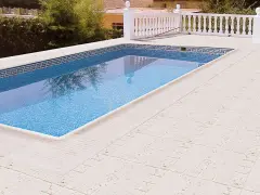 Piscina con borde de mosaico y suelos para piscinas que no quemen, de color claro y textura agradable.