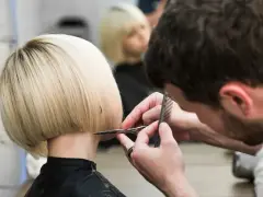 Fryzjerka tworzy modne fryzury odmładzające po 40 krótkie. Blond bob jest precyzyjnie cięty.